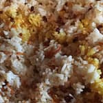 close-up of Persian-style rice: white rice with barberries and shredded carrot, with a drizzle of saffron-infused water turning some rice grains golden