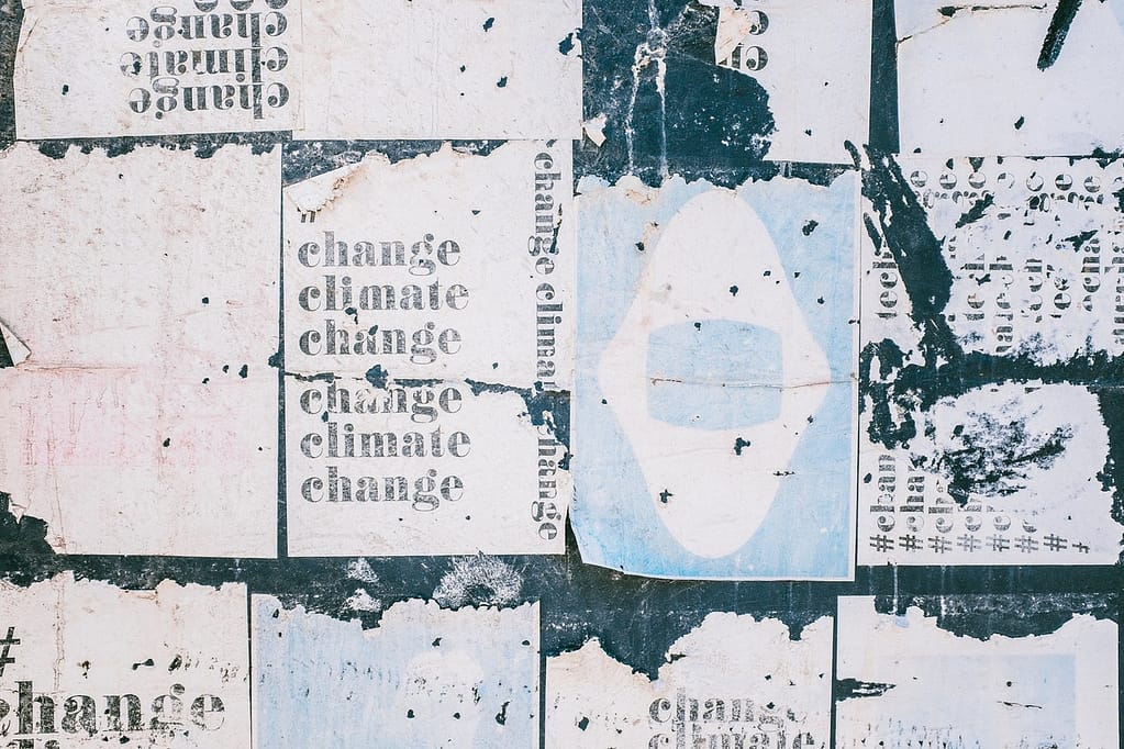 posters plastered on a wall saying "change climate change"