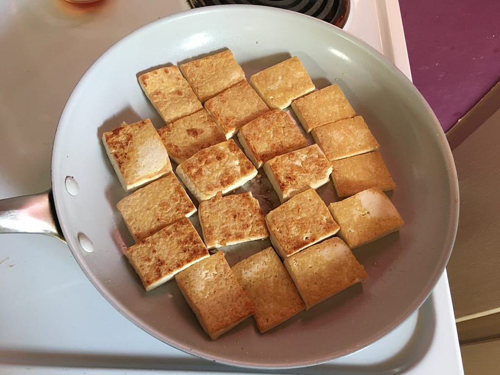 tofu browning in a frying pan