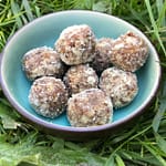 a bowl full of date tahini energy bites in the grass