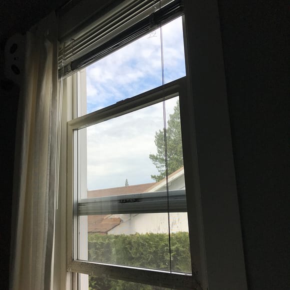 an open window with blue sky, clouds, and trees