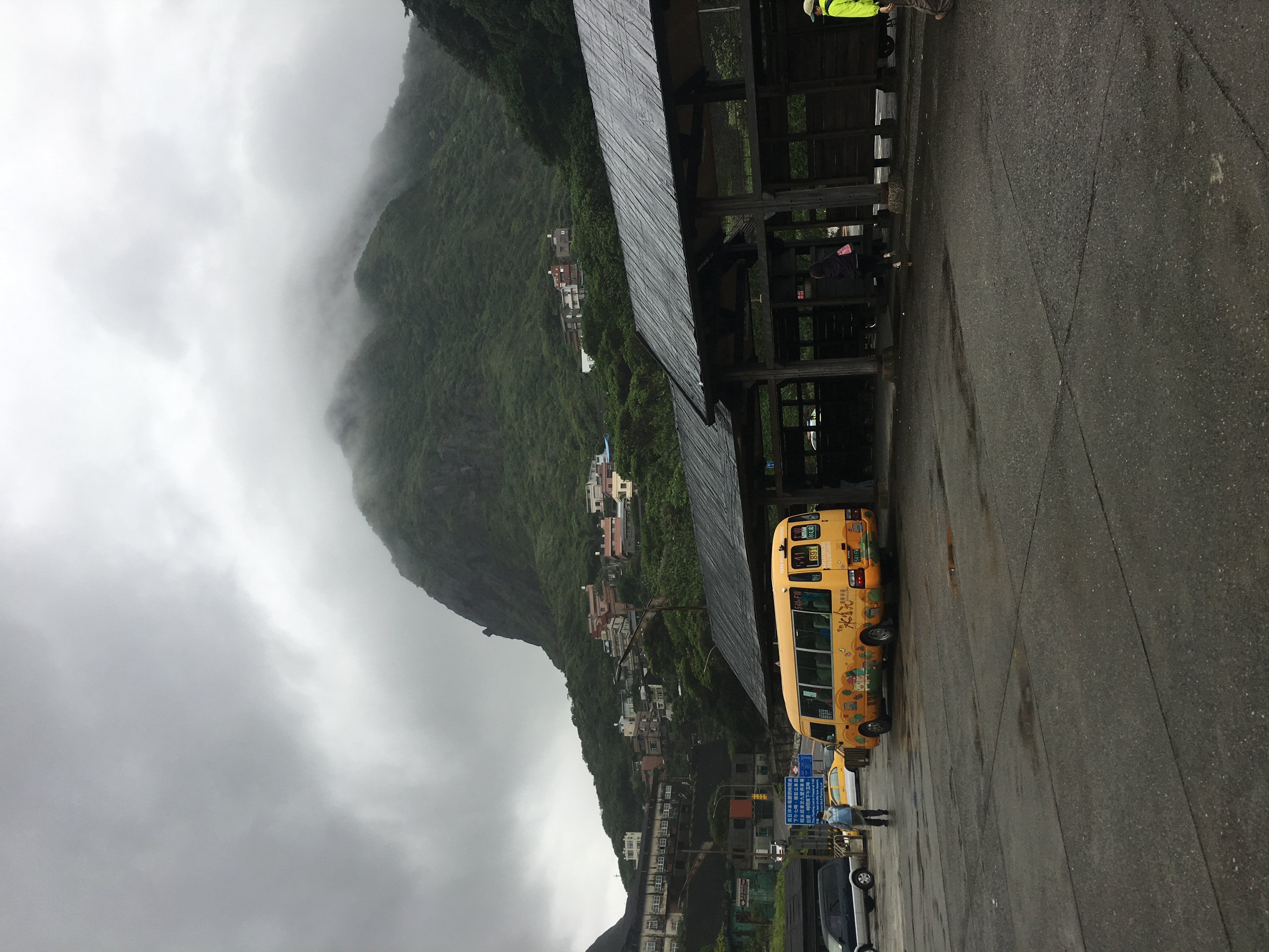 bus station at the base of a green mountain capped with clouds
