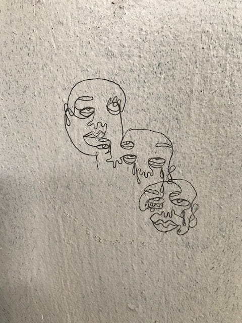 line drawing of connected faces on a wall inside a bunker